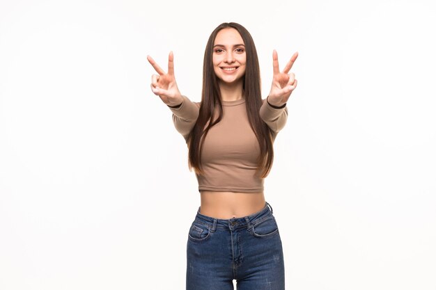 Beautiful young woman showing peace victory sign isolated on white wall