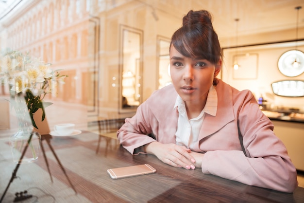 Beautiful young woman sitting at the cafe table