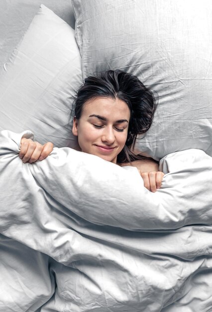 A beautiful young woman sleeps in a white bed