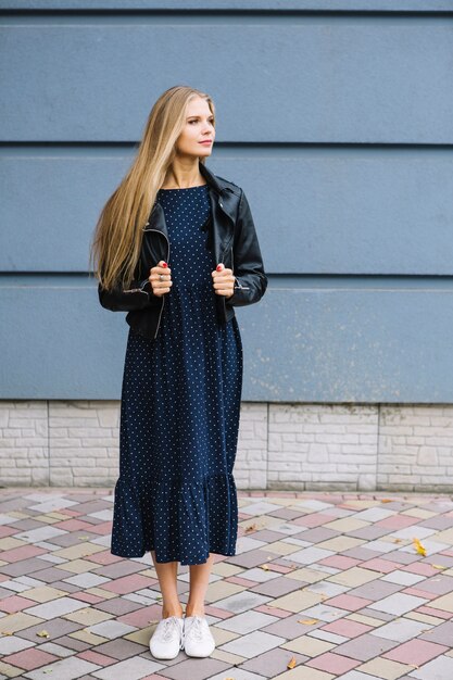 Beautiful young woman standing in front of wall holding wore jacket