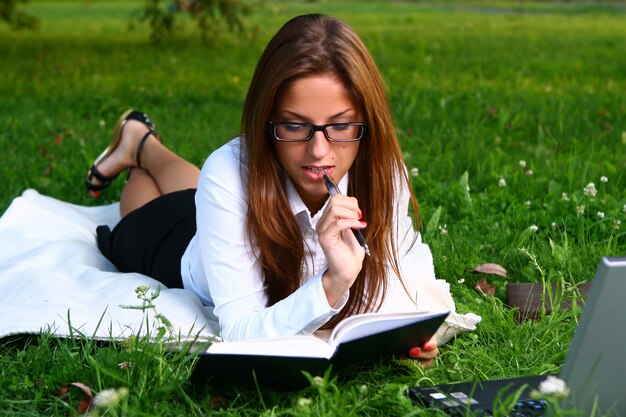 Beautiful young woman studing in park