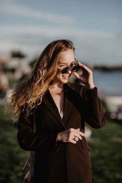 Beautiful young woman in sunglasses in the city at sunset