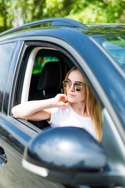 Free photo beautiful young woman in sunglasses driving her car