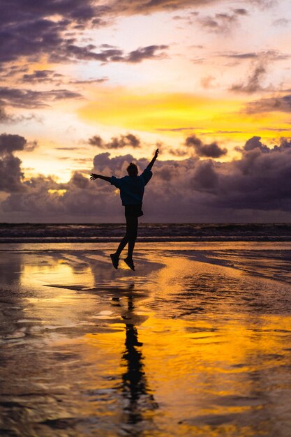 Beautiful young woman at sunset on the ocean, Bali, Indonesia.