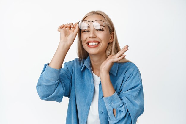 Beautiful young woman taking off glasses smiling and looking excited standing happy against white background Copy space