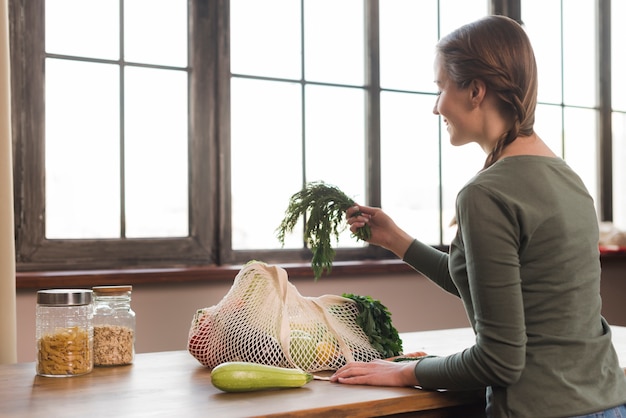 Beautiful young woman taking organic groceries out of bag