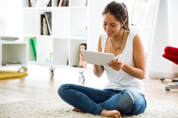 Beautiful young woman using her digital tablet at home.