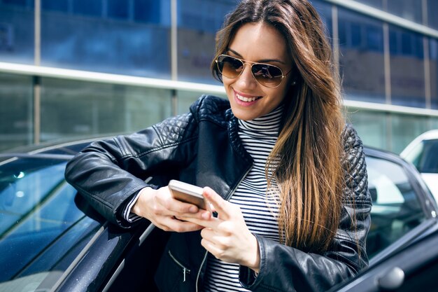 Beautiful young woman using her mobile phone in the car.