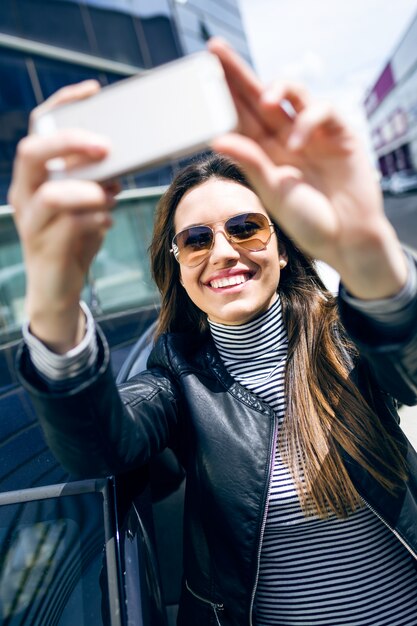 Beautiful young woman using her mobile phone in the car.