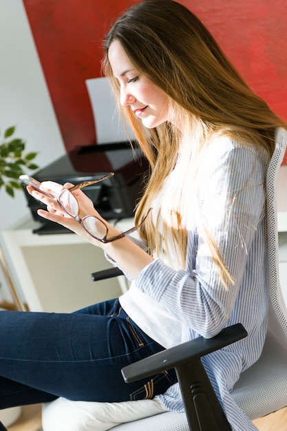 Free photo beautiful young woman using her mobile phone in the office.