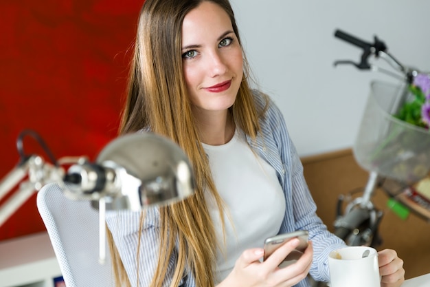 Free photo beautiful young woman using her mobile phone in the office.