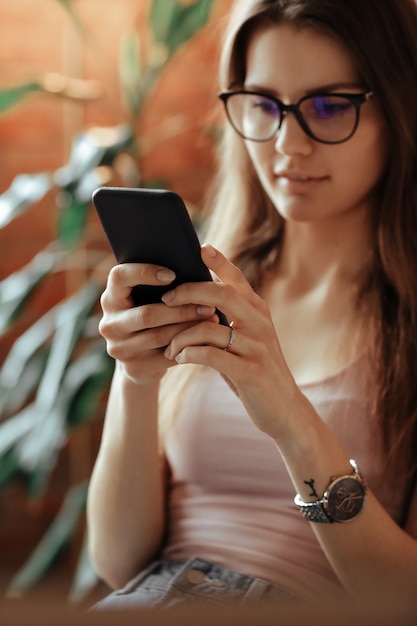 Beautiful young woman using smartphone at home