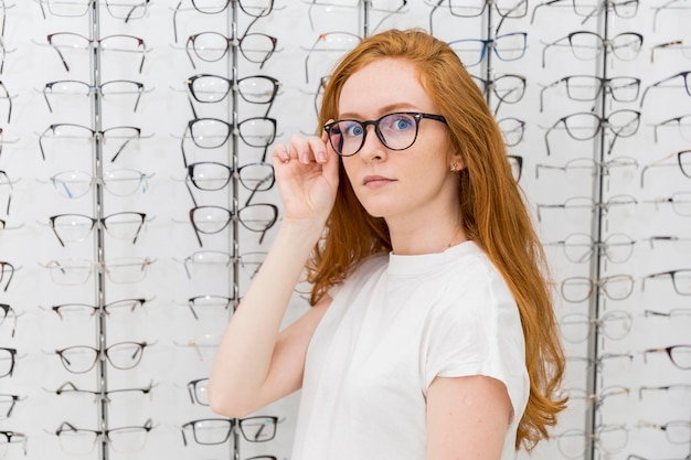 Free photo beautiful young woman wearing eyeglasses looking at camera in optician shop