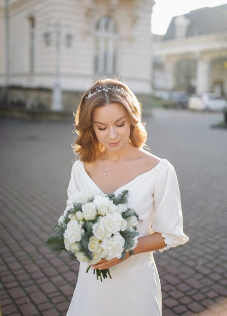 Beautiful young woman in wedding dress posing on the street in city