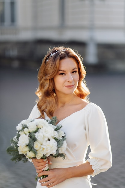 Beautiful young woman in wedding dress posing on the street in city