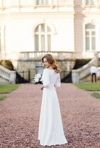 Beautiful young woman in wedding dress posing on the street in city