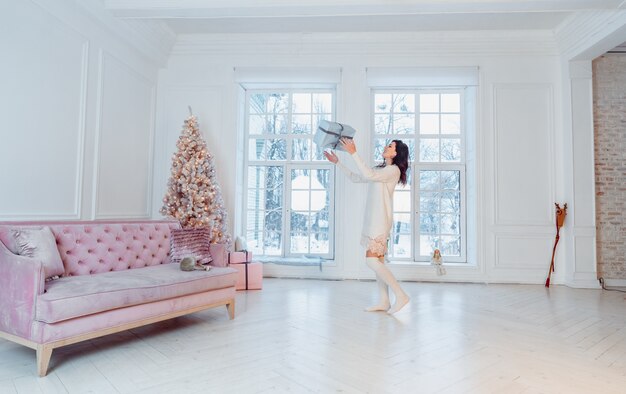 Beautiful young woman in white dress posing with gift box