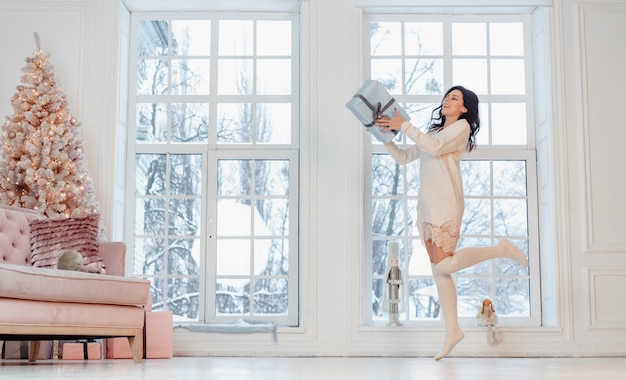 Beautiful young woman in white dress posing with gift box