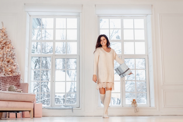 Free Photo beautiful young woman in white dress posing with gift box