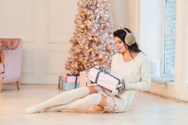 Beautiful young woman in a white dress with gifts in their hands