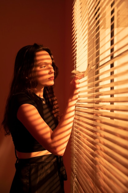 Free photo beautiful young woman behind window blinds