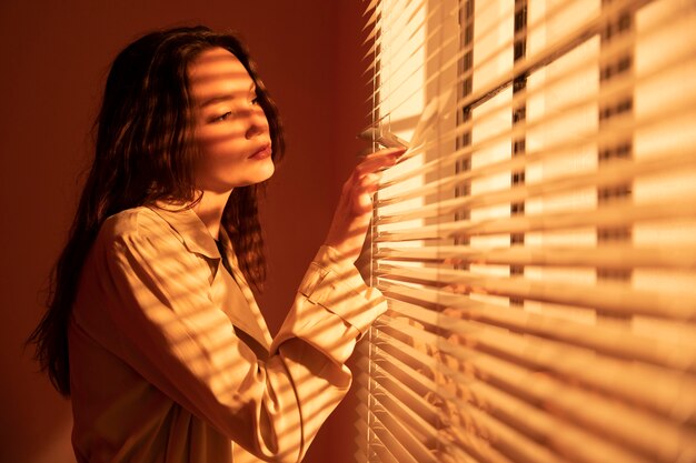 Beautiful young woman behind window blinds