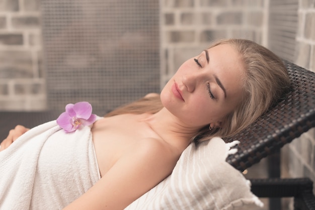 Free photo beautiful young woman with eye closed sleeping on lounge chair