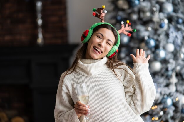 Beautiful young woman with glass of champagne at home. Christmas celebration