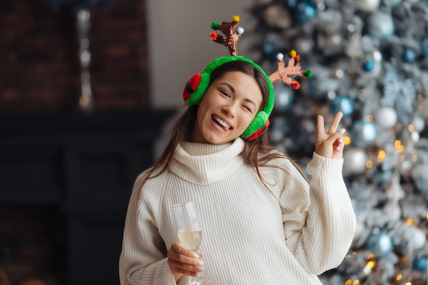 Beautiful young woman with glass of champagne at home