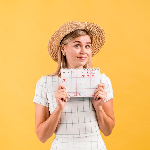 Beautiful young woman with hat showing ovulation calendar