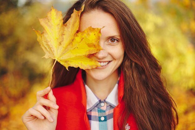 Beautiful young woman with long wavy hair covering face with a leaf