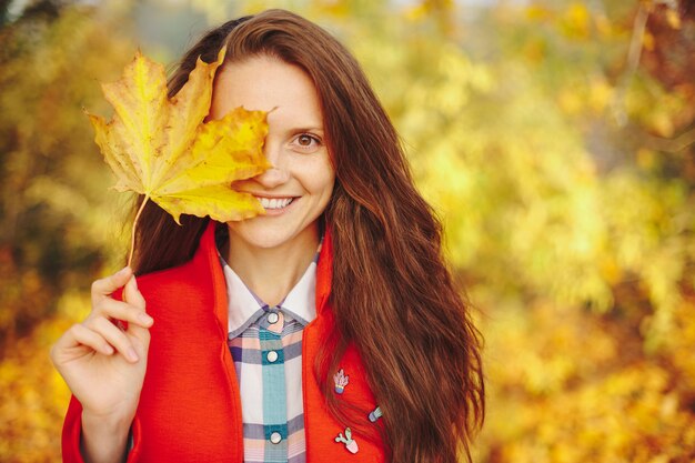 Beautiful young woman with long wavy hair covering face with a leaf