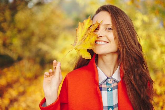 Beautiful young woman with long wavy hair covering face with a leaf