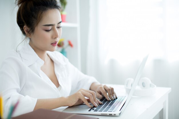 Beautiful young woman working on her laptop in her room.