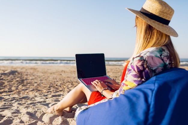 Beautiful young woman working with laptop on the tropical beach