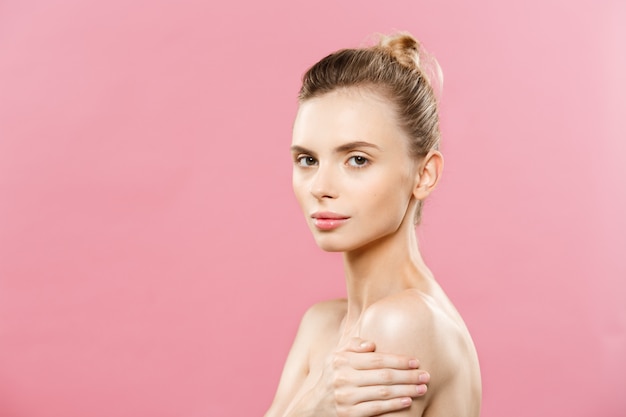 Free photo beauty concept - beautiful caucasian woman with clean skin, natural make-up isolated on bright pink background with copy space.