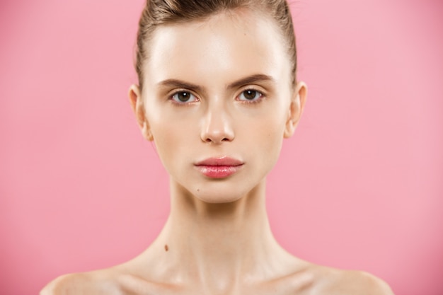 Free photo beauty concept - close up portrait of attractive caucasian girl with beauty natural skin isolated on pink background with copy space.