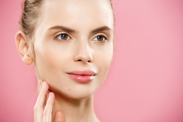 Free photo beauty concept - close up portrait of attractive caucasian girl with beauty natural skin isolated on pink background with copy space.