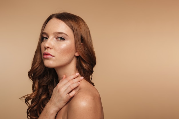 Free photo beauty portrait of calm ginger woman with long hair posing sideways and looking