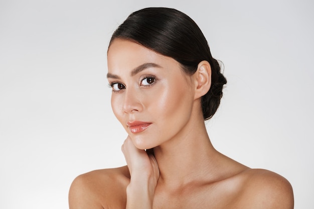 Beauty portrait of charming caucasian woman with brown hair in bun posing at camera with beautiful look, isolated over white