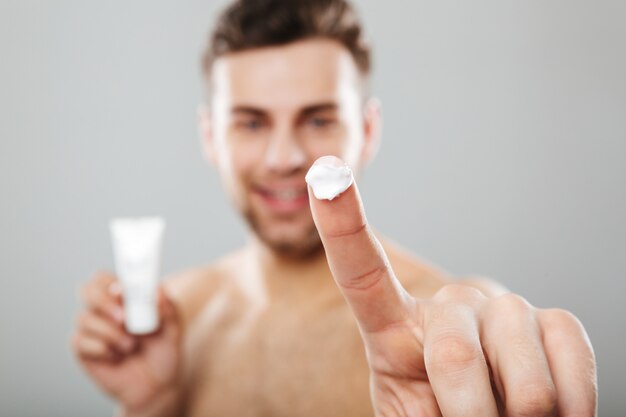 Beauty portrait of a half naked man applying face cream