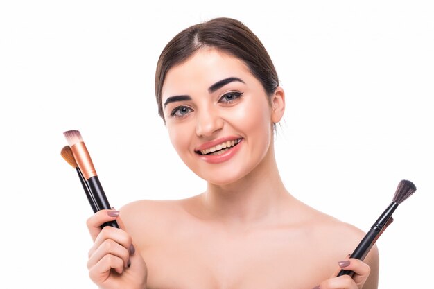 Beauty portrait of a happy beautiful half naked woman holding set of make-up brushes