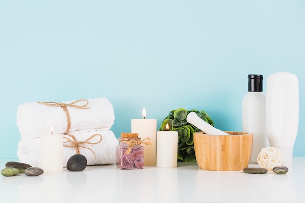 Free Photo beauty products with illuminated candles in front of blue wall