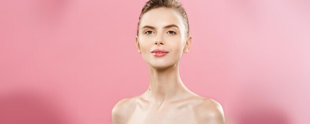 Beauty Spa Concept Caucasian Woman with perfect face skin Portrait Beautiful Brunette Spa Girl showing empty copy space Isolated on pink studio background Proposing a product