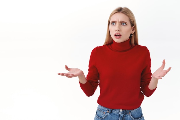 Beauty women and fashion concept Confused and frustrated blond young woman look around cant understand what happening raise hands in dismay gasping worried white background