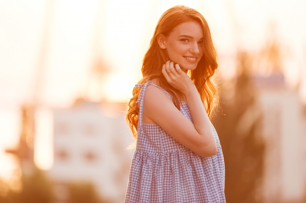 Free Photo beauty young ginger girl in dress posing sideways on sunset