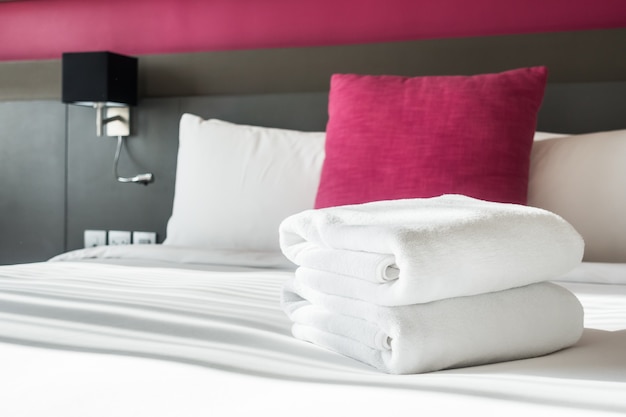 Bed with two white towels and a cushion