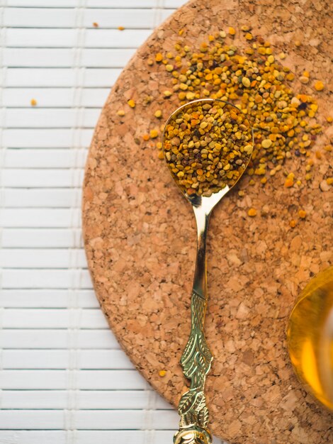 Bee pollens in spoon on cork coasters