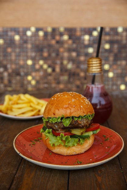 Beef burger with lettuce, fresh and pickled cucumber, tomato, served with fries