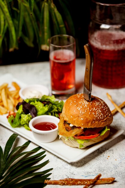 Beef burger with onion rings tomato lettuce served with salad and fries